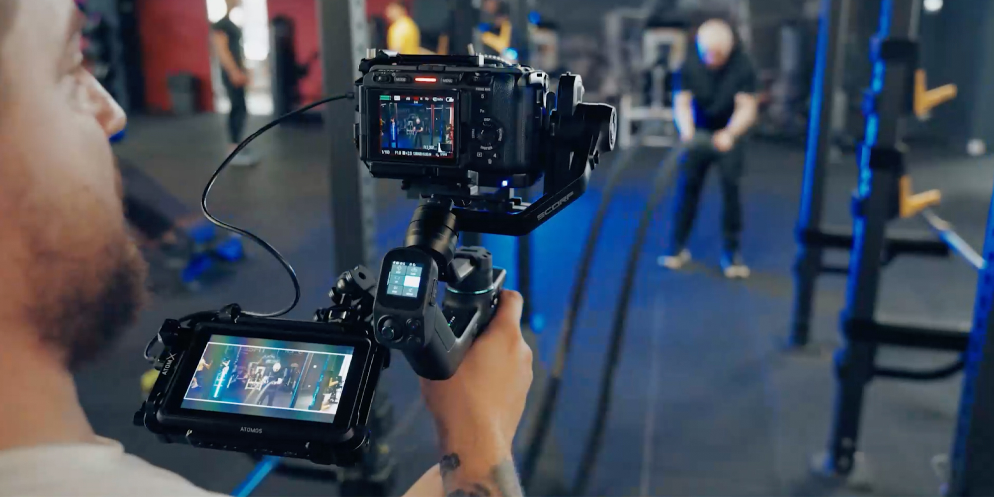 width=100% Gimbal ręczny FeiyuTech Scorp mini 3 Kit podczas nagrywania filmu na siłowni, połączony z aparatem i ekranem podglądowym